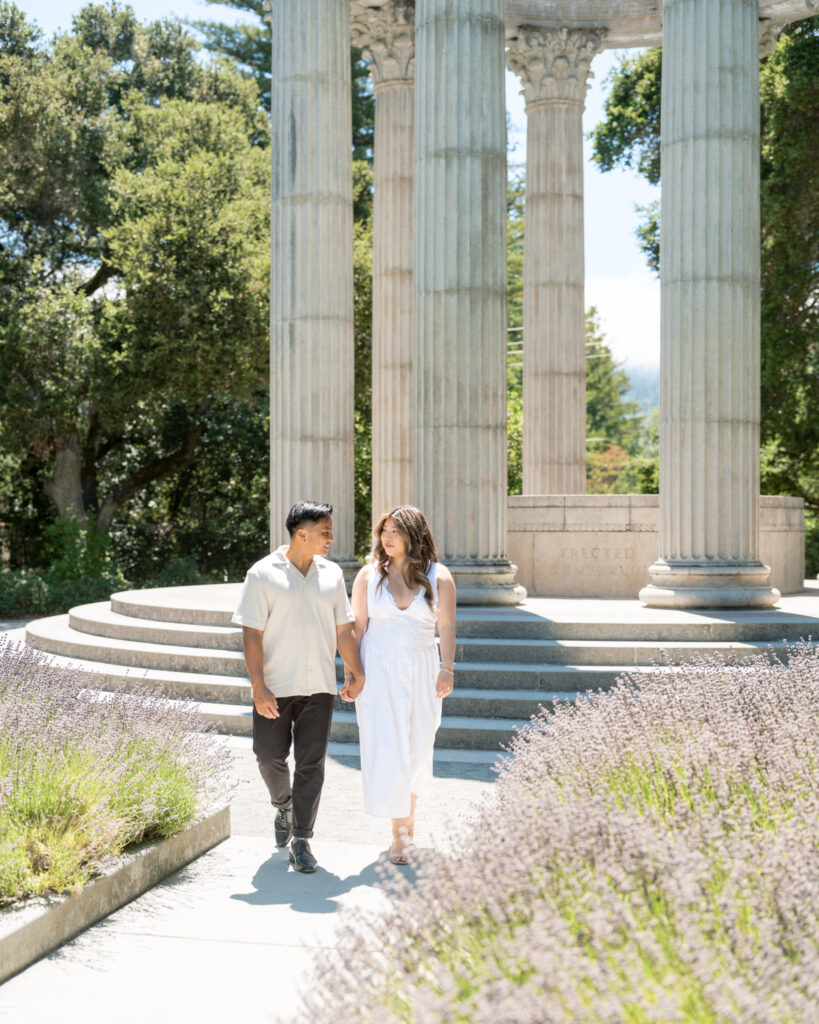 Engaged couple walking and smiling at each other during their engagement session at the Pulgas Water Temple
