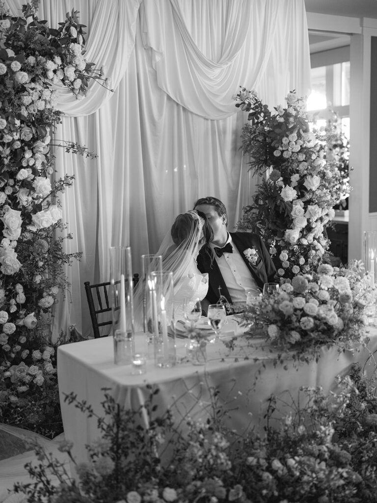 Bride and groom share a kiss at their stunning sweet heart table