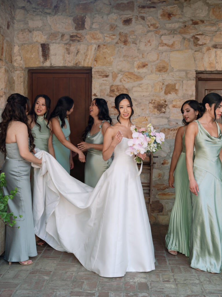 Bride amongst her bridesmaids against the stone walls of Holman Ranch