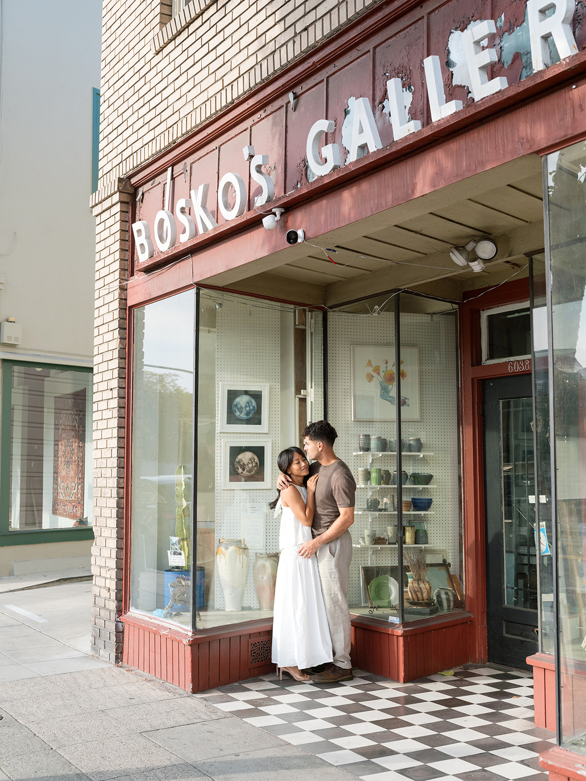 Newly engaged couple pose in front of red building with a pop of color for their downtown Bay Area engagement photos