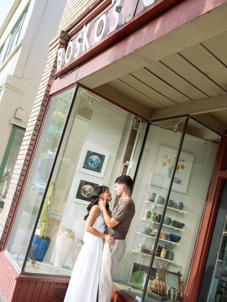 Newly engaged couple pose in front of red building with a pop of color for their downtown Bay Area engagement photos