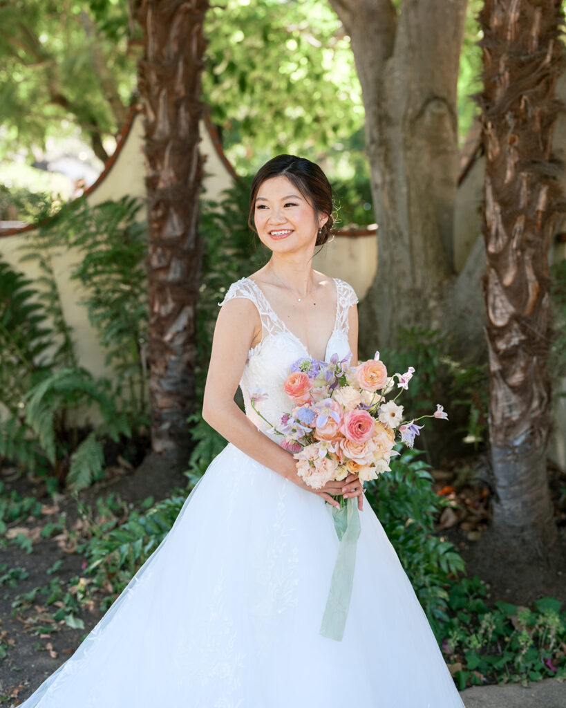 Bride poses amongst garden and palm trees at Allied Arts Guild, a garden Bay Area wedding venue