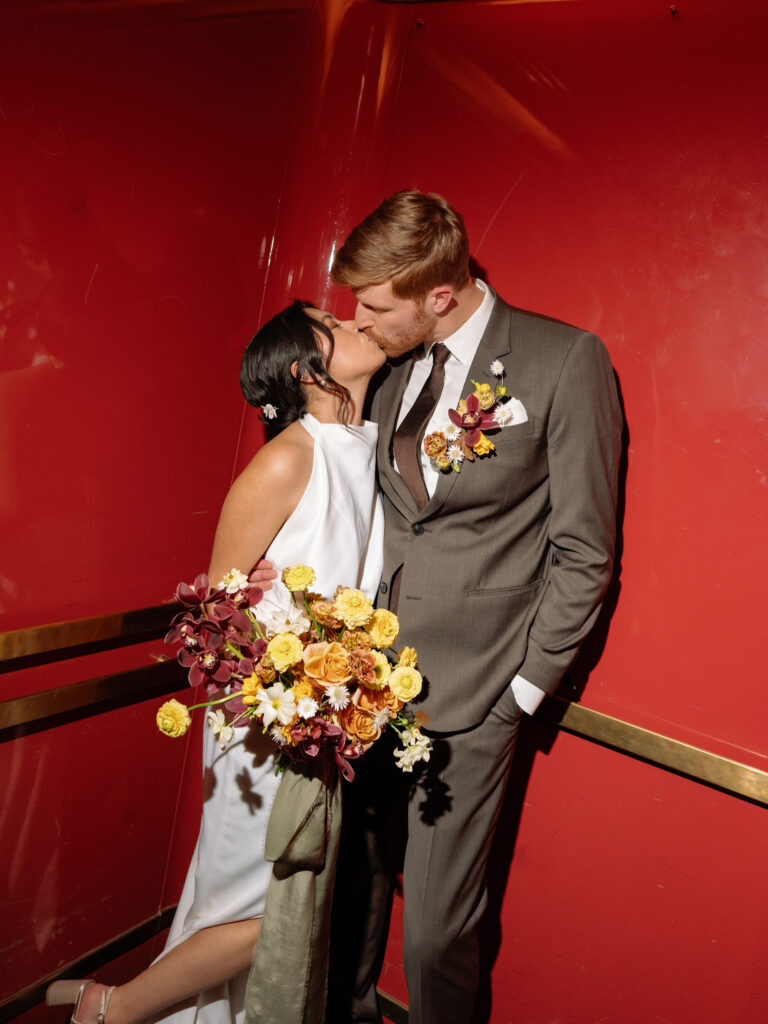 bride and groom sneak in a kiss in the red elevators at the Marin County Civic Center