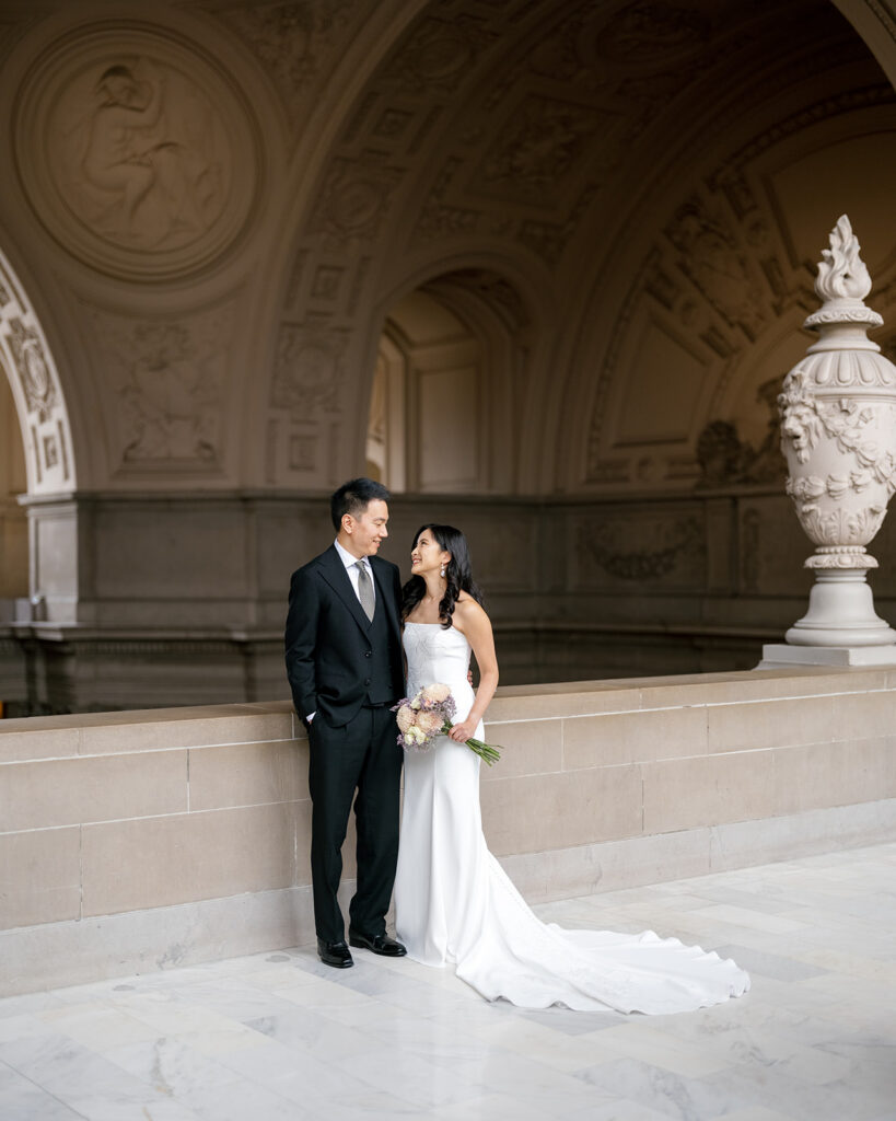 bride in her BHLDN wedding dress, groom in a classic black suit, in the iconic fourth floor balcony of San Francisco City Hall