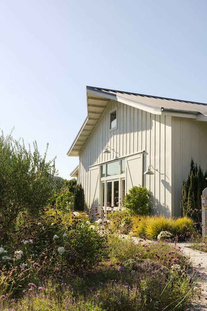 Exterior of The Barn at Harrow Cellars, a Sonoma wedding venue — white board-and-batten barn with metal roof, surrounded by a wildflower and lavender garden