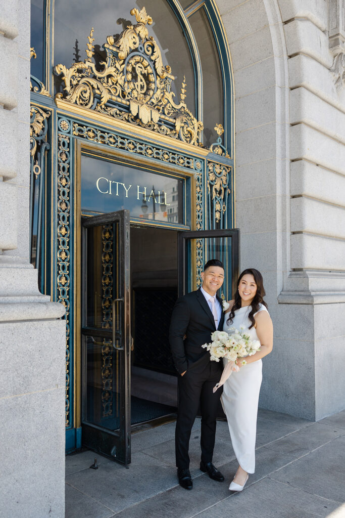 Bride and groom with their dog in the arched entrance at San Francisco City Hall with natural sunlight