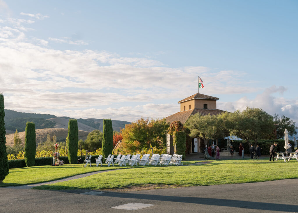 Wide shot of Viansa Winery's outdoor ceremony lawn with guests arriving, cypress trees lining the path and Sonoma hills in the distance — Sonoma wedding photographer