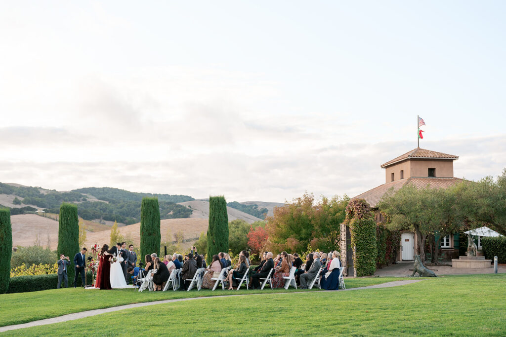 Outdoor wedding ceremony at Viansa Winery, guests seated on white chairs with the Viansa tower and Sonoma hills behind the couple