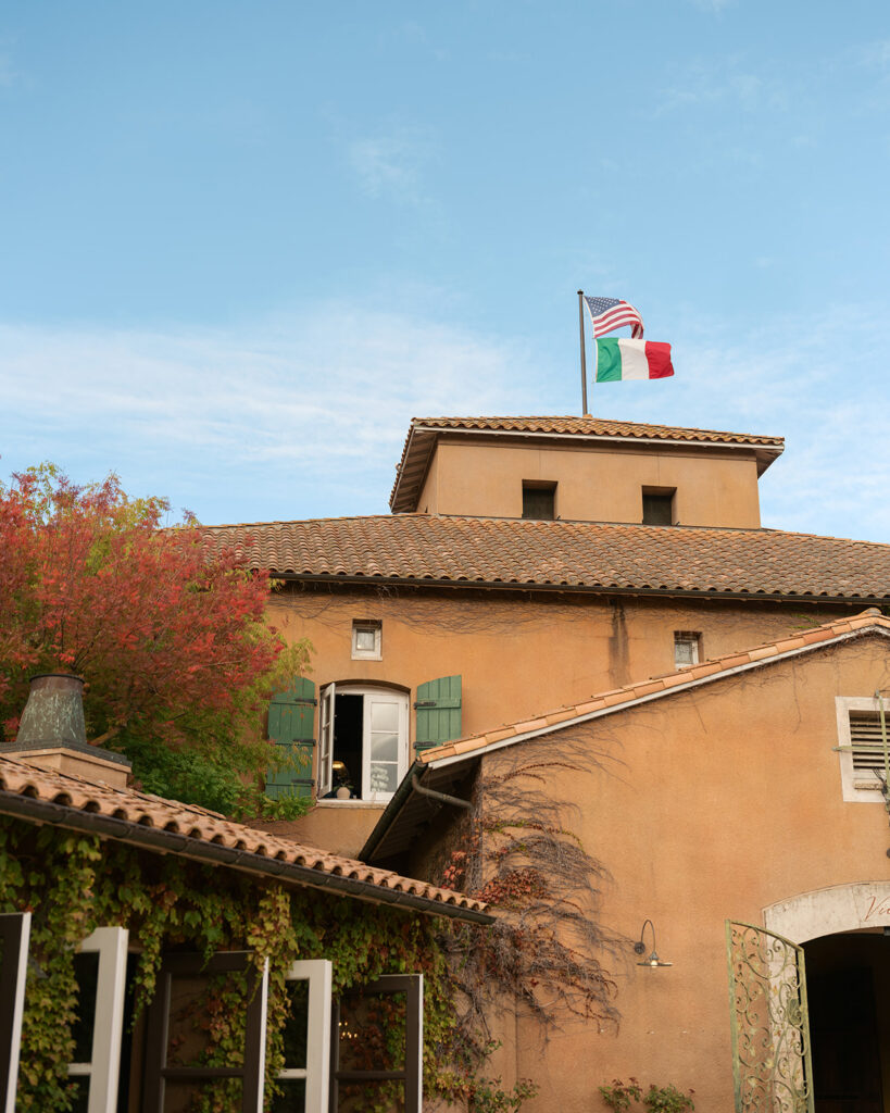 Exterior of Viansa Winery, a Sonoma wedding venue, with terracotta tile roof, Italian and American flags, ivy-covered walls and fall foliage